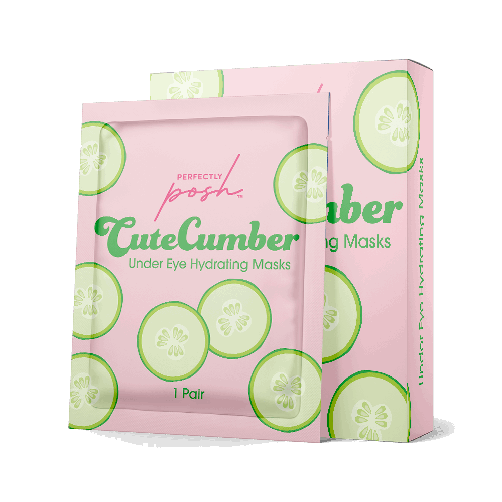 A pink box and matching sachet labeled “CuteCumber Under Eye Hydrating Masks - Perfectly Posh” feature cucumber slice graphics. Designed to brighten eyes and reduce puffiness, the packaging notes “1 Pair” for under eye skincare.