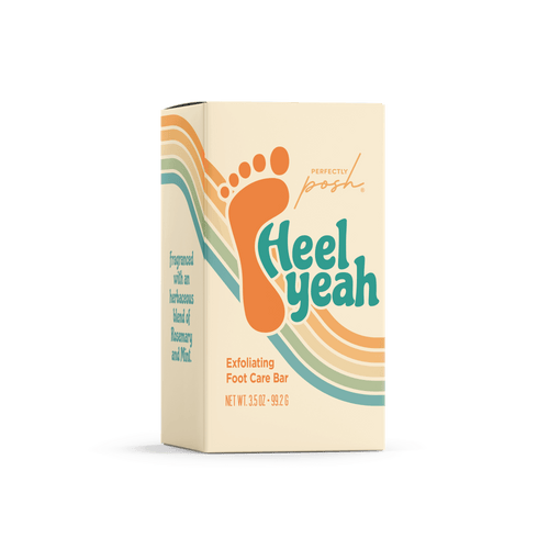 A cream-colored box labeled "Heel Yeah Bar - Perfectly Posh" by Perfectly Posh features an orange footprint, colorful stripes, and herbaceous rosemary & mint scent. Net weight: 3.25 oz (92 g).