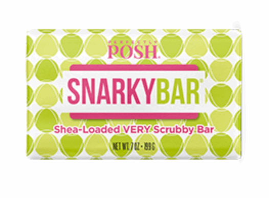 A rectangular bar package labeled "Snarky Shea-Loaded VERY Scrubby Bar - Perfectly Posh" shows a pink and green design with a green and white geometric background. This 7 oz (199 g) Perfectly Posh scrub delivers exfoliating bliss.