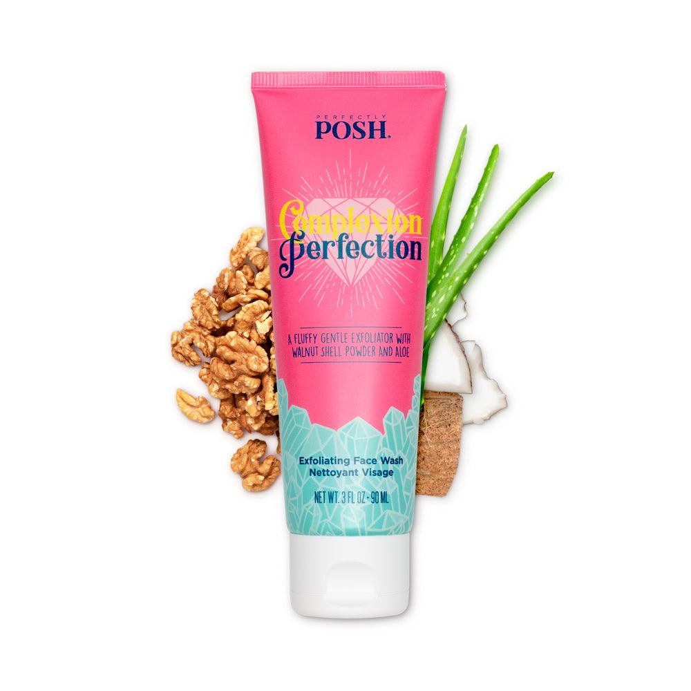 A pink and turquoise tube of Perfectly Posh's Complexion Perfection Exfoliating Face Wash is pictured with walnut pieces, coconut, and an aloe vera leaf on a white background, emphasizing its gentle exfoliation benefits.