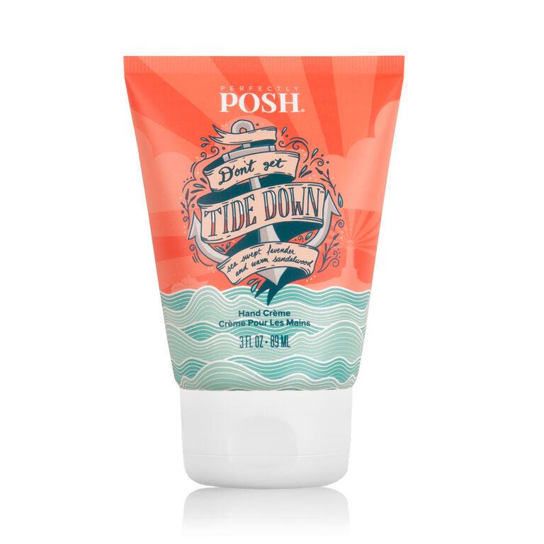 A tube of Perfectly Posh Don't Get Tide Down hand creme features a coral and teal wave design, sunburst accents, and a soothing lavender sandalwood scent with apricot kernel oil.