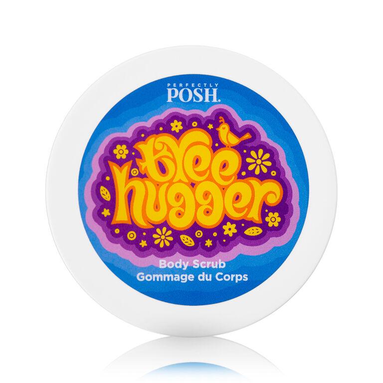 A round container of Perfectly Posh Tree Hugger Body Scrub, featuring a colorful retro-style label with a bird and flowers—this natural exfoliator boasts bright yellow and orange text on a blue background for standout style.